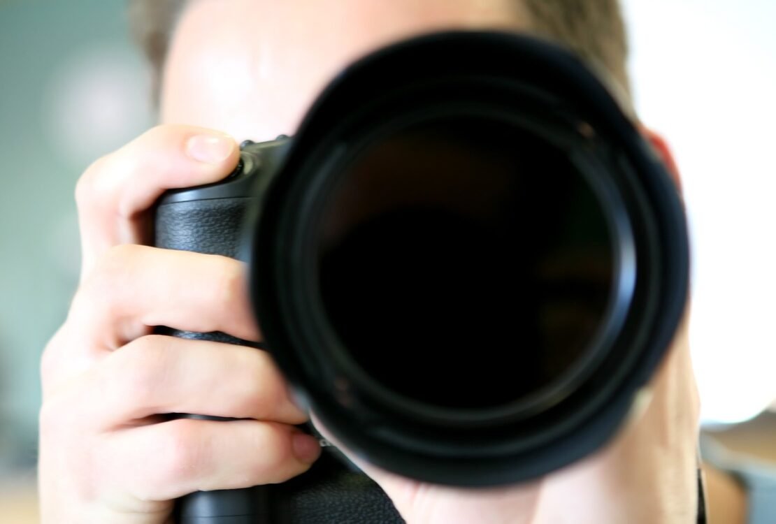 Person fotografiert mit einer Kamera mit großem Objektiv