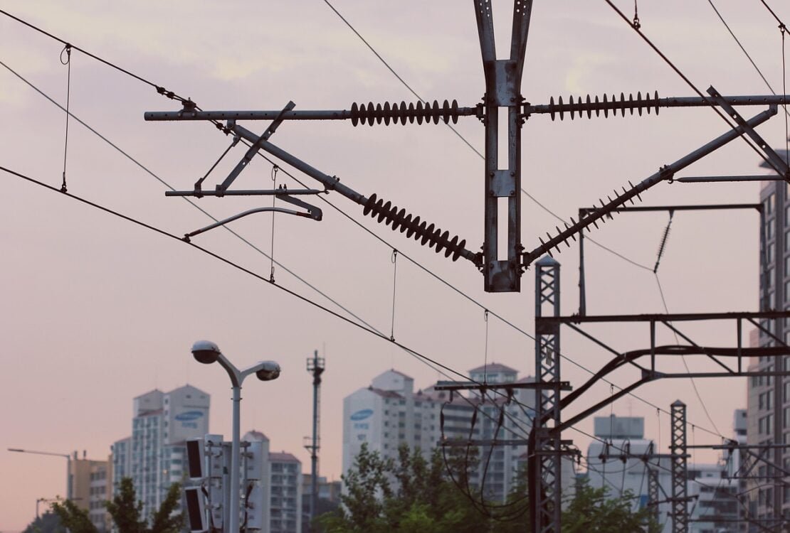 Oberleitungsmasten vor einer Stadtsilhouette