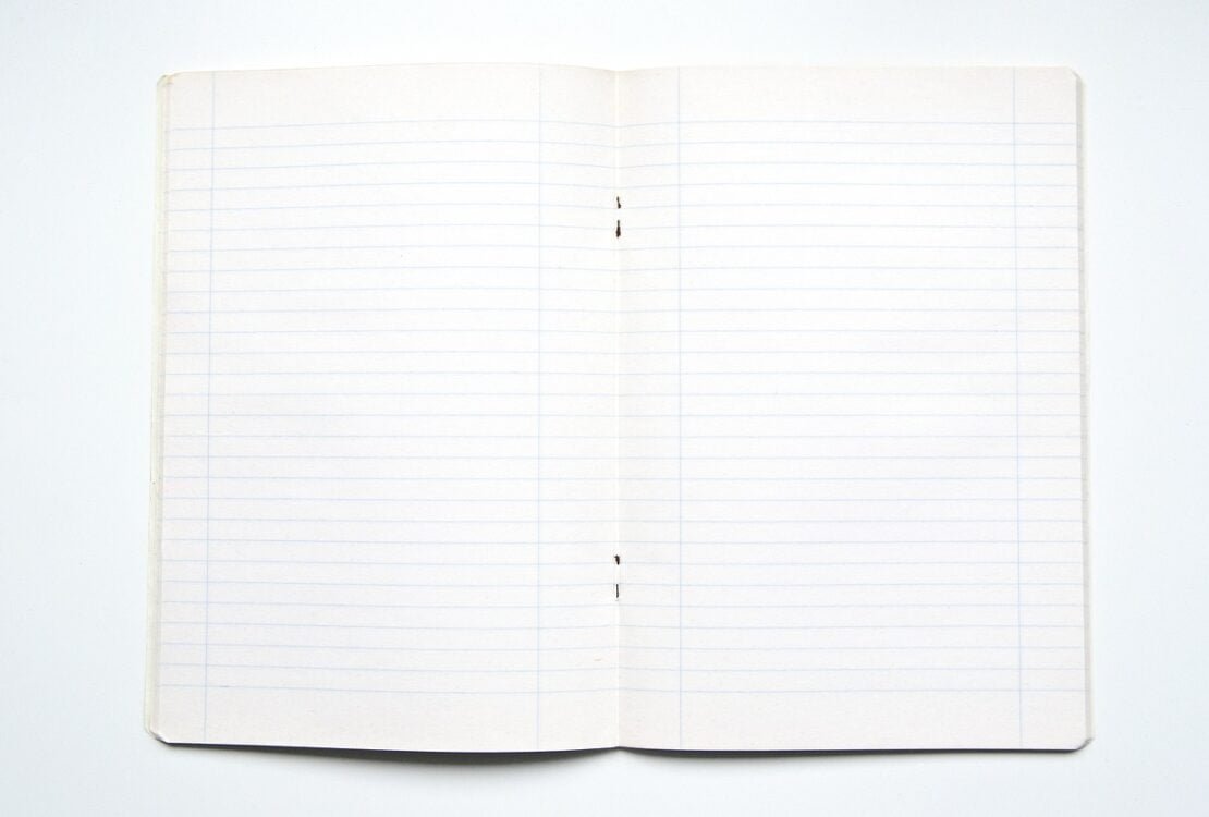 Aufgeschlagenes liniertes Notizbuch auf weißem Grund