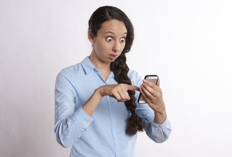 Frau blickt überrascht auf ihr Smartphone
