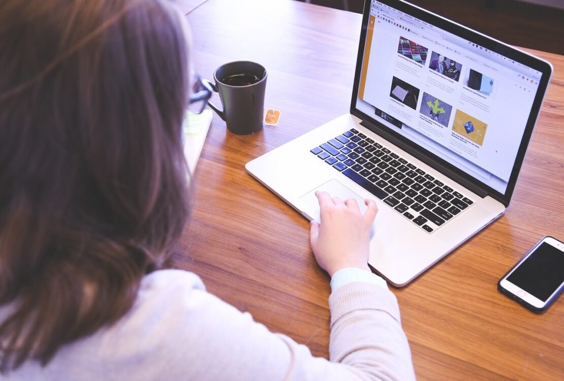 Frau arbeitet von hinten gesehen an einem Laptop