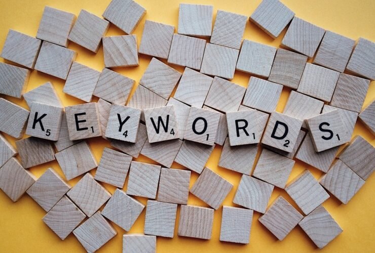 Buchstabensteine bilden das Wort Keywords auf gelbem Grund