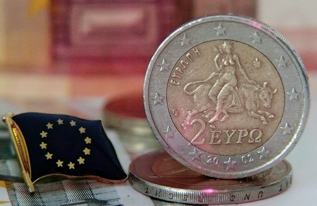 Euro-Münze liegt auf einer kleinen Europaflagge