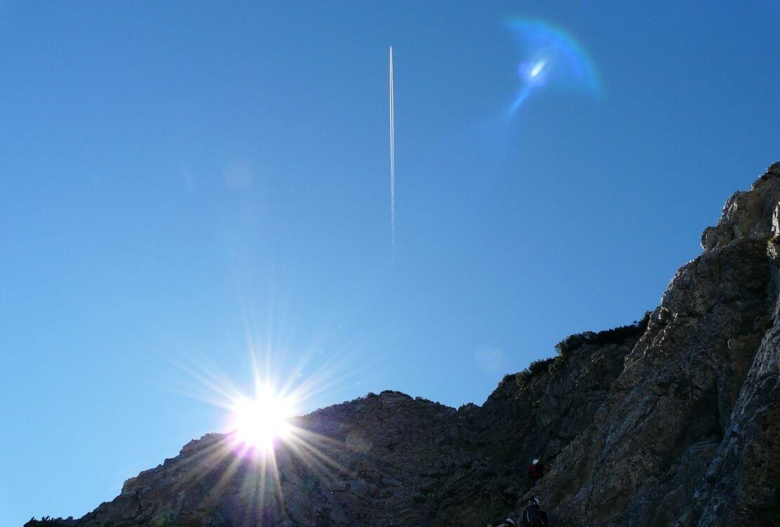 Sonne steht tief über einem dunklen Berghang