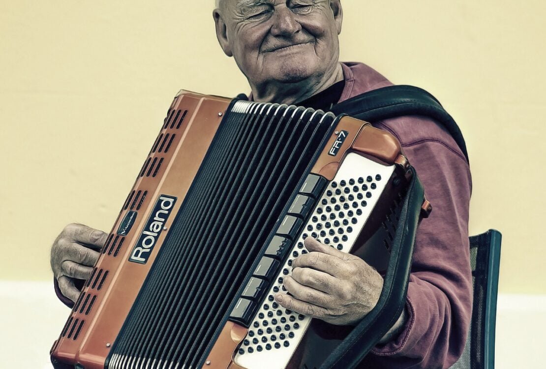 Älterer Mann mit Baskenmütze spielt Akkordeon