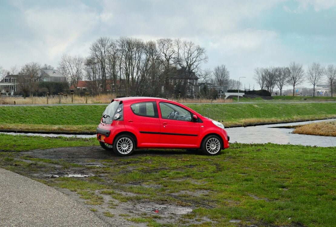 Roter Kleinwagen steht auf einem Feldweg