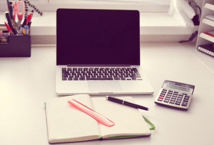 Schreibtisch mit Laptop, Notizbuch und Taschenrechner