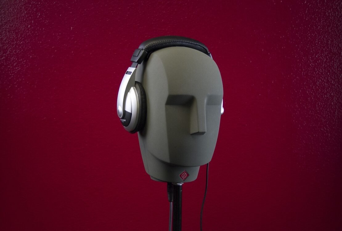 Graue Maske mit Kopfhörer vor rotem Hintergrund