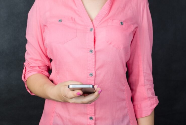 Frau in rosa Hemd hält ein Smartphone