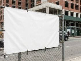 Großformatiges Werbebanner an einem Bauzaun mit sichtbaren Ösen und Kabelbindern